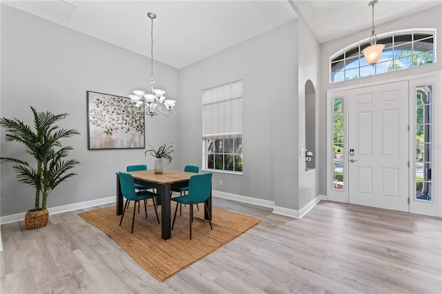 10517 Palm Cove Ave, Tampa, FL 33647 - dining room featuring baseboards, arched walkways, a high ceiling, and light wood-type flooring