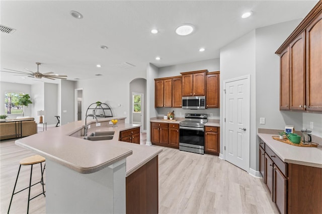 10517 Palm Cove Ave, Tampa, FL 33647 - kitchen with light countertops, arched walkways, a sink, light wood-style flooring, and appliances with stainless steel finishes