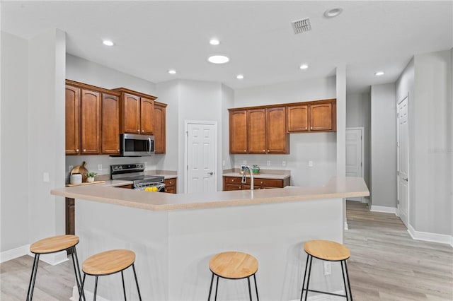 10517 Palm Cove Ave, Tampa, FL 33647 - kitchen featuring visible vents, a kitchen breakfast bar, light countertops, light wood-style flooring, and stainless steel appliances