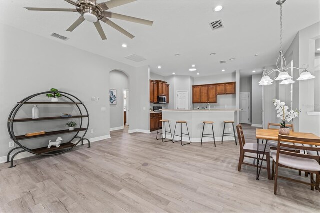 10517 Palm Cove Ave, Tampa, FL 33647 - dining room featuring arched walkways, ceiling fan with notable chandelier, light wood-type flooring, and visible vents