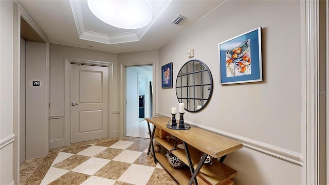 corridor featuring visible vents, ornamental molding, and a raised ceiling