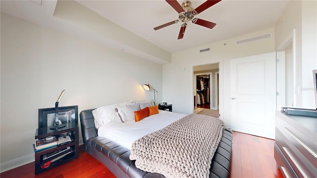 bedroom with ceiling fan, visible vents, and wood finished floors