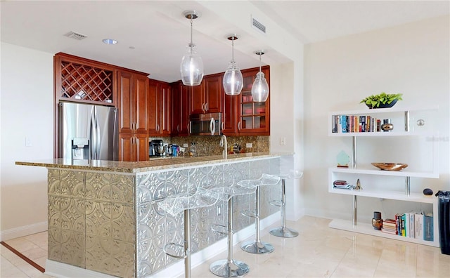 kitchen with backsplash, visible vents, appliances with stainless steel finishes, baseboards, and reddish brown cabinets