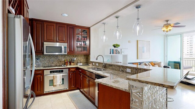 kitchen with appliances with stainless steel finishes, a sink, a peninsula, a ceiling fan, and a kitchen bar