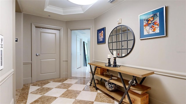 corridor featuring ornamental molding, a tray ceiling, and light tile patterned flooring