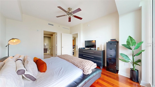 bedroom featuring ensuite bath, baseboards, visible vents, and light wood-type flooring