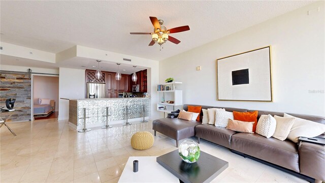 living area featuring a ceiling fan, a barn door, and light tile patterned floors