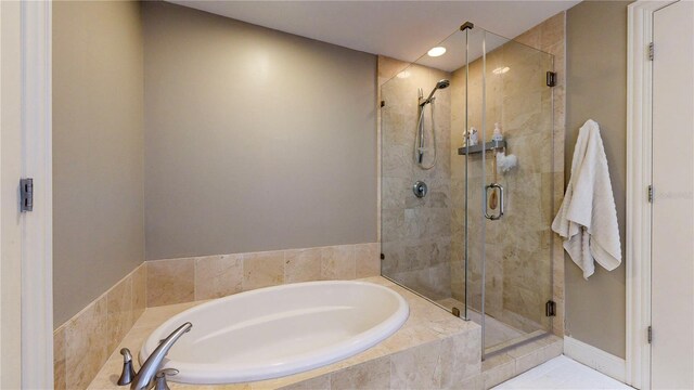 bathroom featuring recessed lighting, a bath, and a stall shower