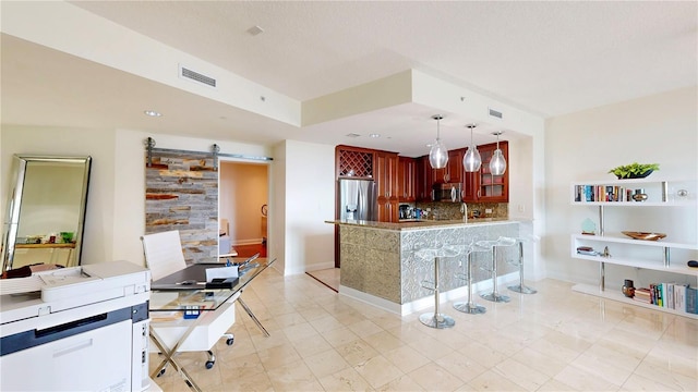 kitchen with decorative backsplash, visible vents, a barn door, dark brown cabinets, and stainless steel appliances