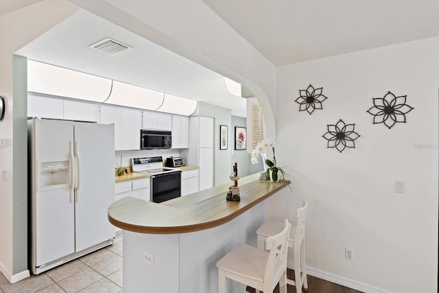 7120 N Croton Pt, Hernando, FL 34442 - kitchen with visible vents, baseboards, a peninsula, a breakfast bar, and white appliances