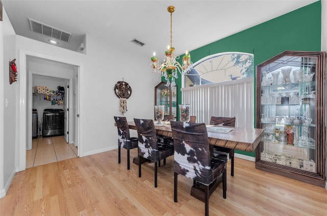 12923 Colony Rd, Hudson, FL 34669 - dining space featuring washing machine and clothes dryer, visible vents, wood finished floors, and an inviting chandelier