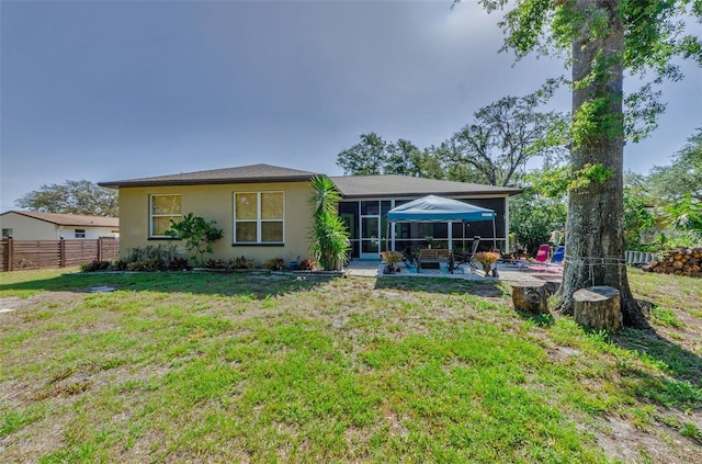12923 Colony Rd, Hudson, FL 34669 - back of property featuring fence, stucco siding, a sunroom, a lawn, and a patio