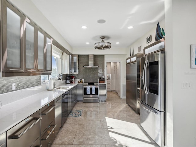 kitchen featuring backsplash, a sink, glass insert cabinets, stainless steel appliances, and wall chimney exhaust hood