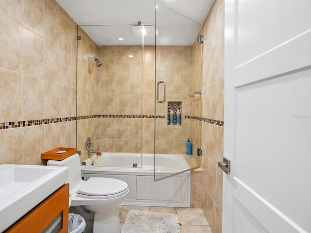 bathroom featuring tile walls, tile patterned flooring, bath / shower combo with glass door, vanity, and toilet