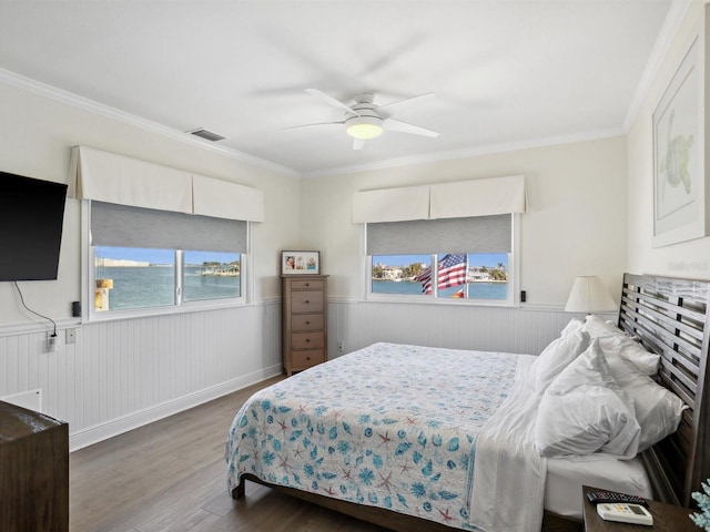 bedroom featuring crown molding, visible vents, wainscoting, and wood finished floors