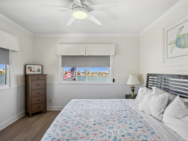 bedroom with multiple windows, wood finished floors, and a wainscoted wall