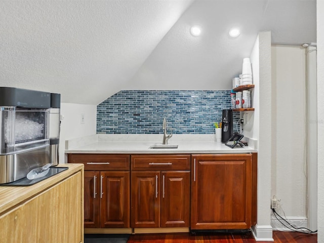 kitchen with light countertops, a textured ceiling, a sink, and lofted ceiling