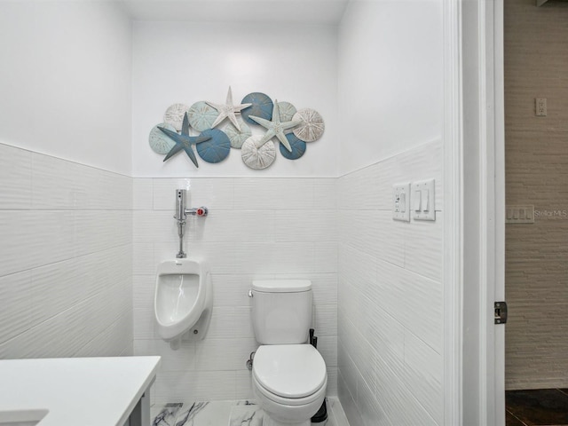 bathroom with wainscoting, toilet, and tile walls