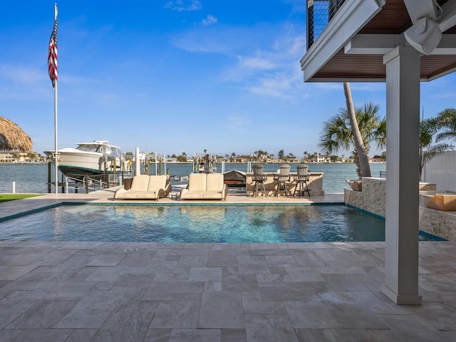 pool with a patio, a water view, boat lift, and a dock