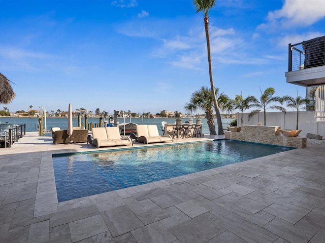 outdoor pool with a water view and a patio area
