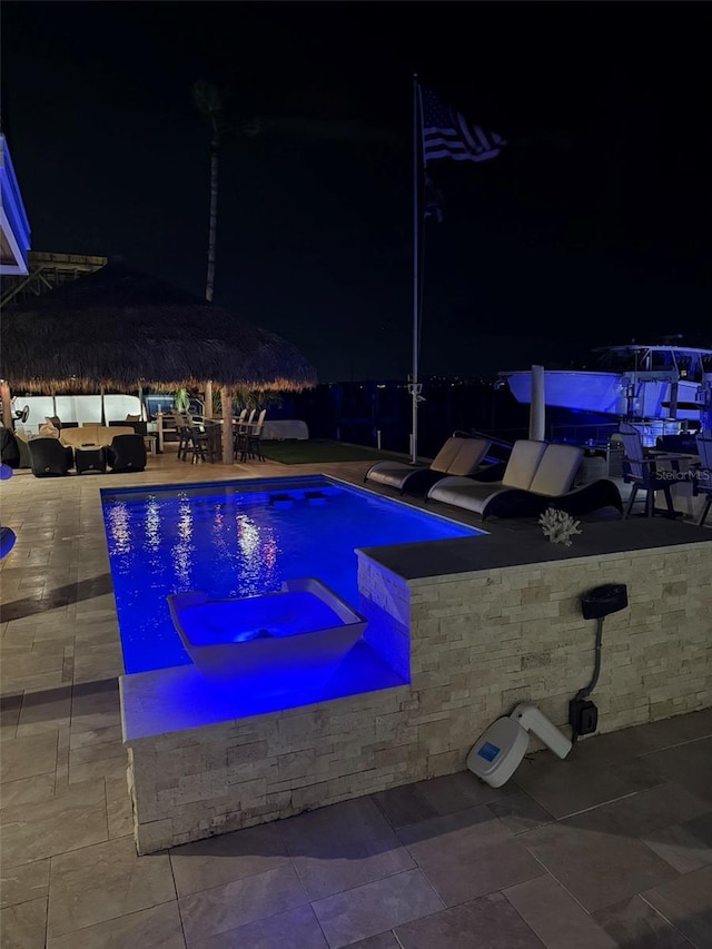 pool at twilight with a jacuzzi, a patio area, and an outdoor pool