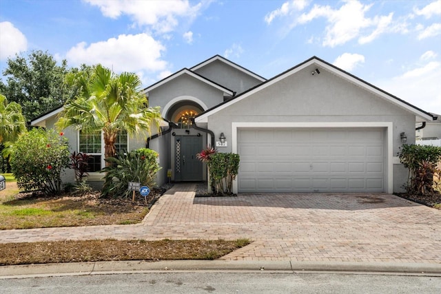 ranch-style home featuring an attached garage, decorative driveway, and stucco siding