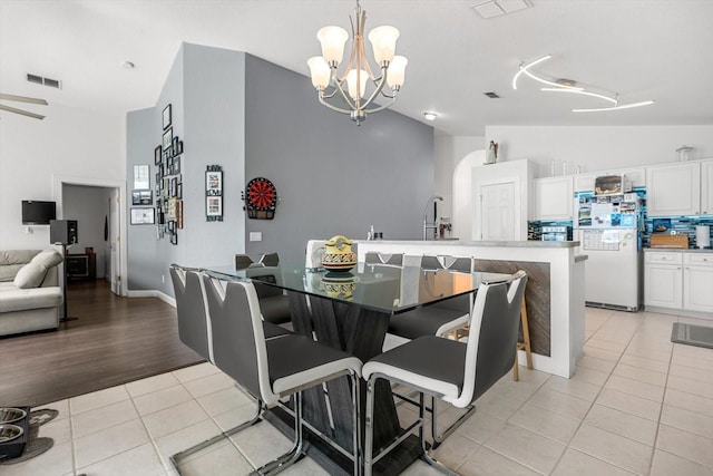 dining space with visible vents, lofted ceiling, light tile patterned floors, and an inviting chandelier