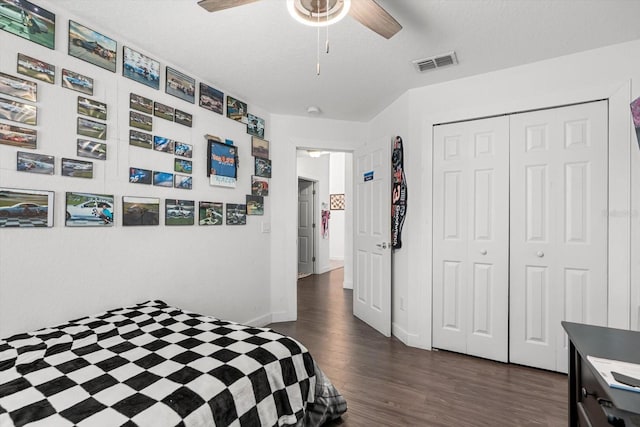 bedroom featuring a ceiling fan, visible vents, baseboards, a closet, and dark wood-type flooring