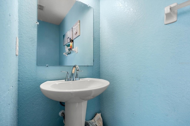bathroom with visible vents and a textured wall