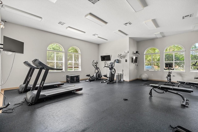 exercise room with a textured ceiling, visible vents, and baseboards