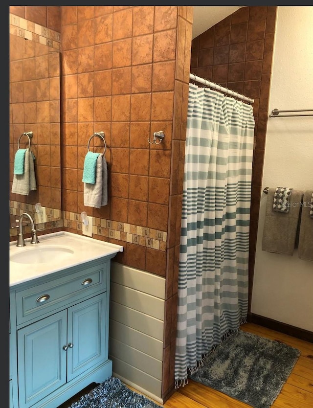 bathroom with wood finished floors, curtained shower, tile walls, and vanity