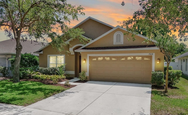 view of front of home featuring a garage, stucco siding, a yard, and concrete driveway