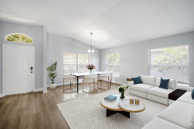 living room featuring baseboards, a chandelier, wood finished floors, and lofted ceiling