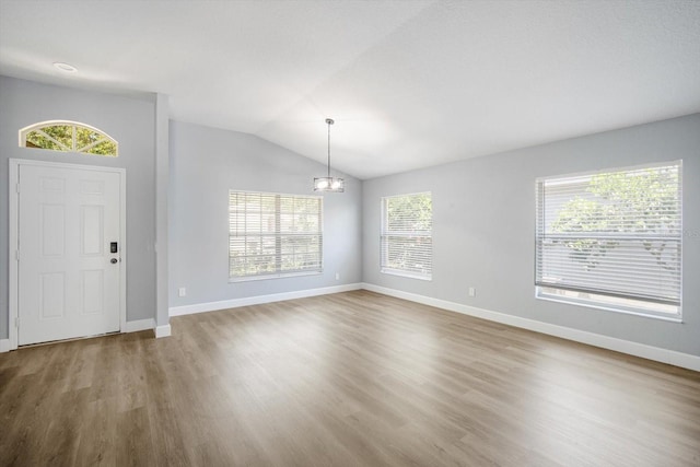 foyer entrance with an inviting chandelier, baseboards, and wood finished floors