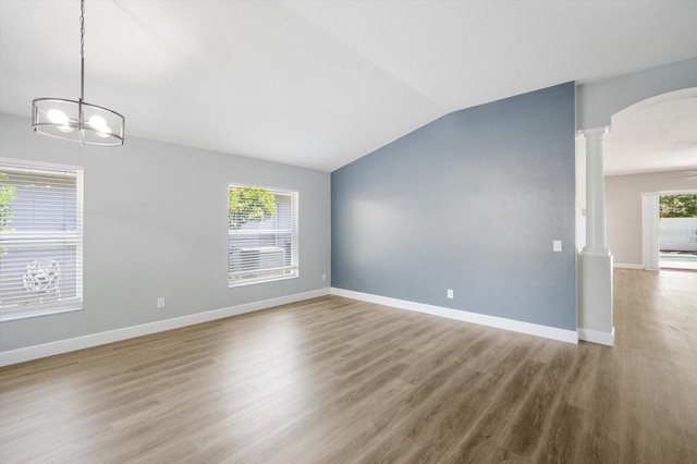 interior space with decorative columns, wood finished floors, lofted ceiling, a chandelier, and arched walkways