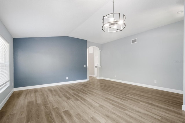 empty room featuring visible vents, an inviting chandelier, baseboards, light wood finished floors, and vaulted ceiling