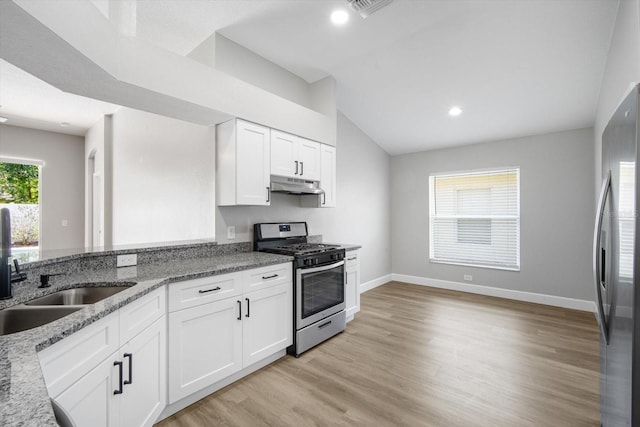 kitchen featuring appliances with stainless steel finishes, light stone counters, lofted ceiling, under cabinet range hood, and white cabinetry