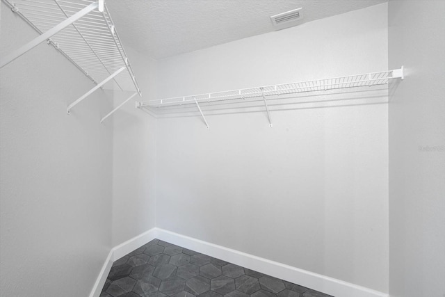 walk in closet with visible vents and dark tile patterned flooring