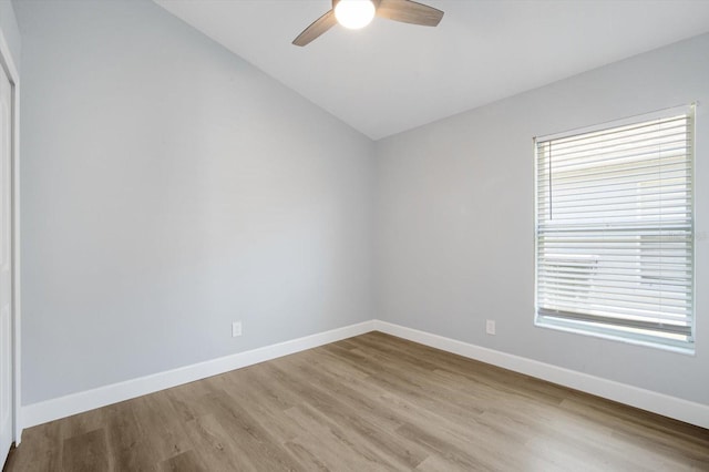 spare room with baseboards, a ceiling fan, light wood-style flooring, and lofted ceiling