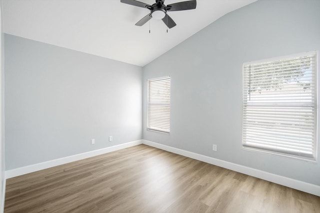 spare room featuring baseboards, ceiling fan, vaulted ceiling, and light wood-type flooring