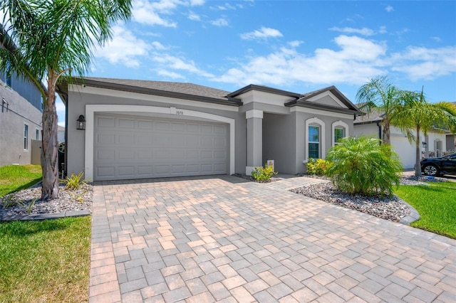 view of front of home featuring an attached garage, decorative driveway, and stucco siding