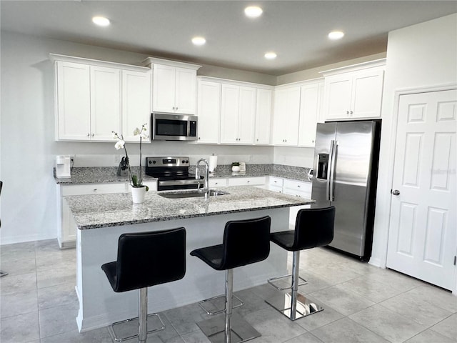 kitchen featuring a breakfast bar area, stainless steel appliances, an island with sink, and a sink