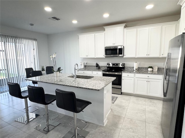 kitchen with visible vents, appliances with stainless steel finishes, a sink, a breakfast bar, and white cabinetry