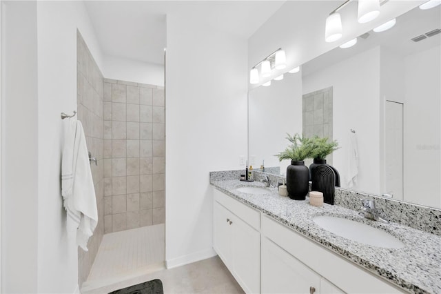 bathroom featuring double vanity, a walk in shower, visible vents, and a sink