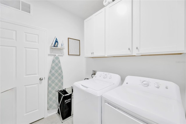 clothes washing area with visible vents, cabinet space, and washer and dryer