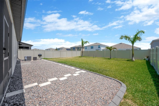 view of yard with central AC unit, a fenced backyard, and a residential view