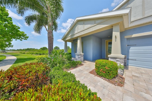 entrance to property with covered porch, stone siding, and stucco siding