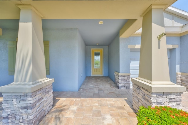view of exterior entry featuring stone siding and stucco siding