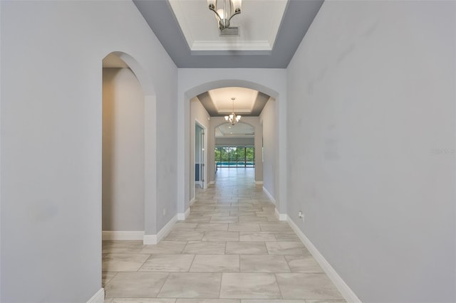 hall featuring visible vents, arched walkways, a raised ceiling, baseboards, and a notable chandelier