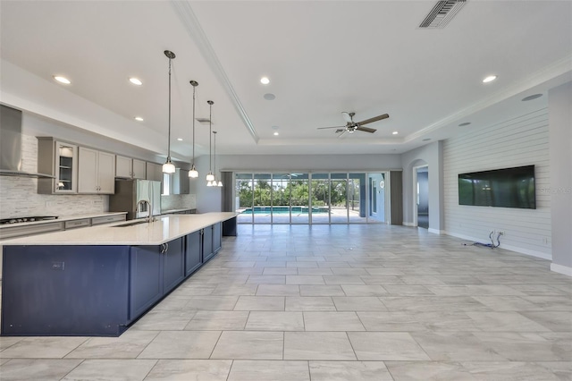kitchen featuring ceiling fan, a raised ceiling, light countertops, open floor plan, and visible vents